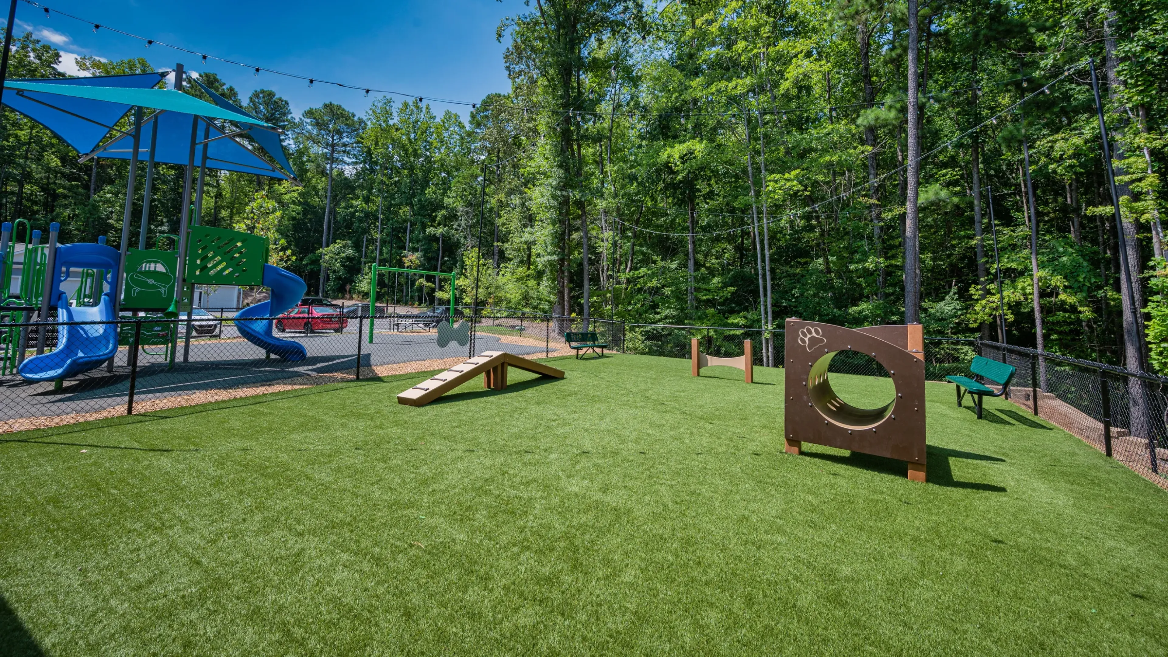 Hawthorne at Parkside outdoor dog park with agility equipment at twilight with pretty lights overhanging the area