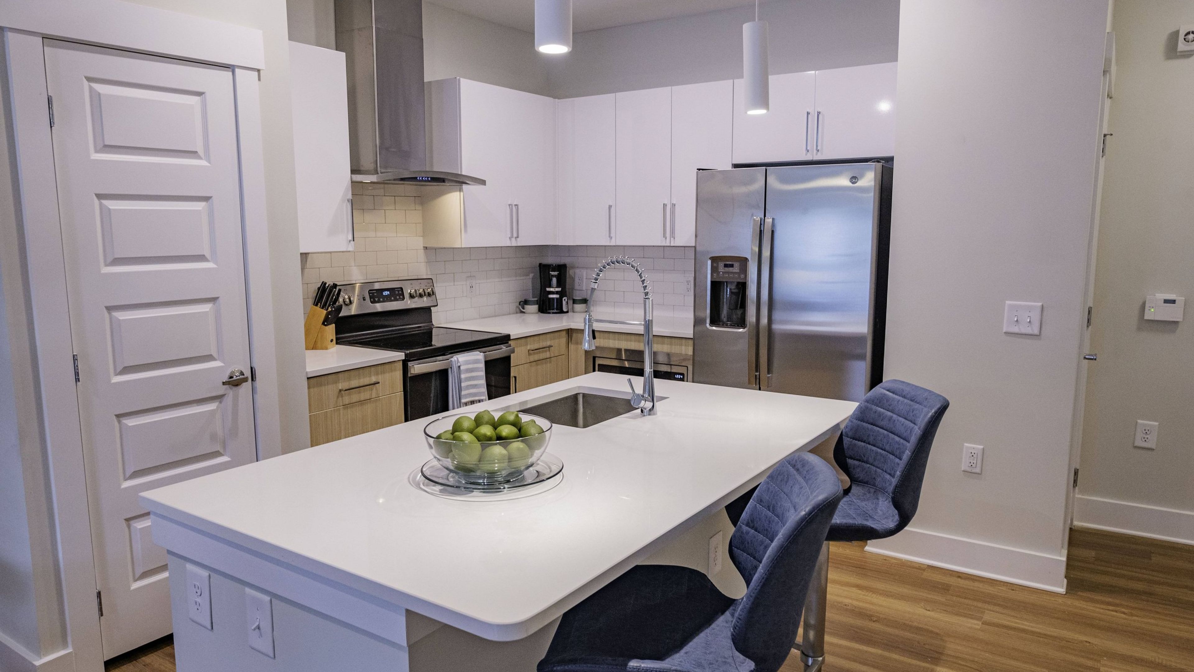 Hawthorne at Parkside luxury apartment kitchen with kitchen island, stainless steel appliances, subway tile backsplash, and designer cabinetry